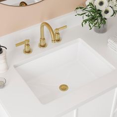 a bathroom sink with gold faucet and soap dispenser next to it