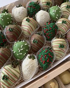 chocolate covered strawberries are in a box with green and red decorations on them, along with other desserts