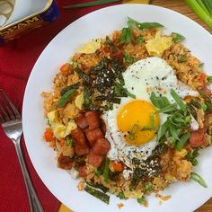 a white plate topped with rice and an egg on top of it next to a fork