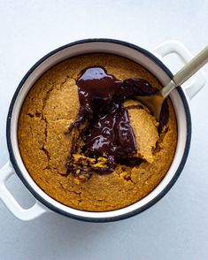 a cookie in a pot with chocolate sauce on top and a spoon sticking out of it