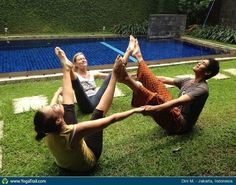 three people doing yoga in front of a swimming pool with their feet up on the ground