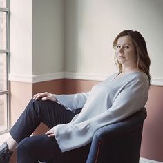 a woman sitting in a chair looking out the window