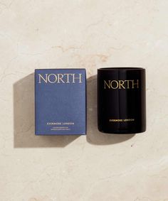 a candle next to a book on a marble surface with the word north printed on it