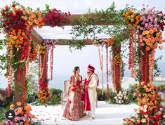 a bride and groom are standing under an archway decorated with flowers