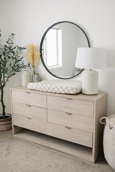 a dresser with a mirror, lamp and vase on it