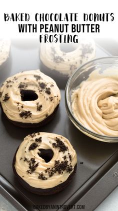 three chocolate donuts with peanut butter frosting on a baking sheet in front of some cupcakes