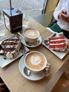 two plates with cakes and coffee on them sitting on a table next to each other