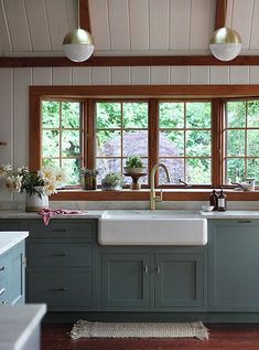 a kitchen with green cabinets and white counter tops is shown in front of a window