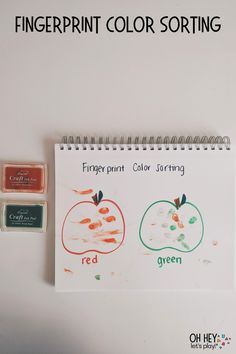 the fingerprint color sorting book is next to a stamp pad with an orange and green apple on it