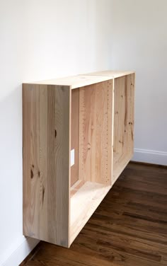 a wooden shelf sitting on top of a hard wood floor next to a white wall