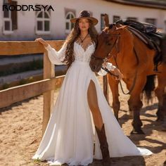 a woman standing next to a horse wearing a long white dress and cowboy hat with her hand on the bridle