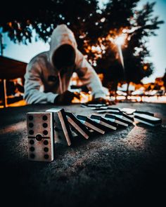 a man kneeling down next to dominos on the ground