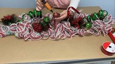 a woman is making christmas decorations on a table