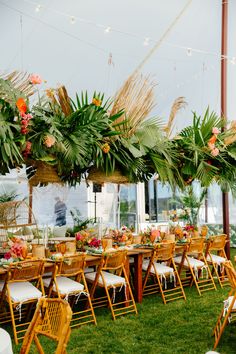 tables and chairs are set up for an outdoor event with hanging plants on the ceiling