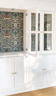 a kitchen with white cabinets and floral wallpaper