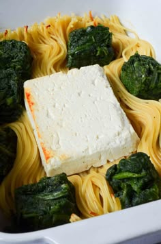 a white dish filled with pasta, spinach and fettuccine