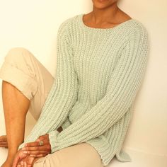 a woman sitting on the floor wearing a sweater