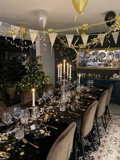 a dining room table set for christmas dinner with gold and silver decorations on the wall