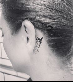 a woman's left ear has a small bird tattoo on it