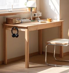 a wooden desk with headphones on it next to a chair and window sill