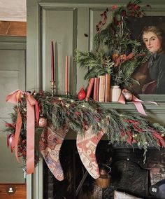 a fireplace mantel decorated for christmas with stockings and candles