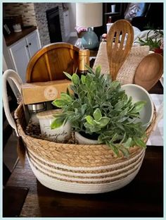 a basket filled with kitchen items on top of a wooden table next to a potted plant