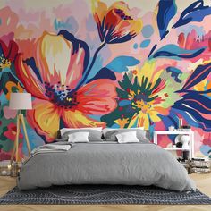 a bedroom with colorful flowers painted on the wall and bed in front of it,