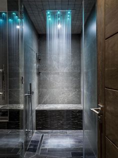 a bathroom with a glass shower stall and tiled flooring, along with a wooden door