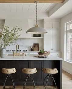 two stools are in front of the kitchen island with an island countertop and pendant lights