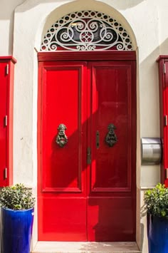 two blue planters are next to a red door