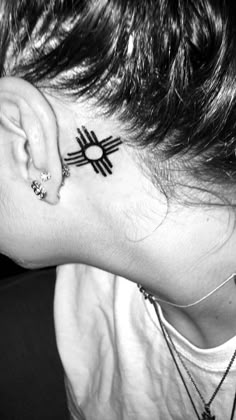 a woman with a tattoo on her neck and behind the ear is a small sun