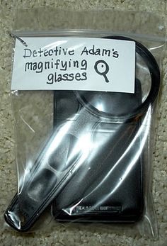 a magnifying glass in its package on the floor next to a sign that says, detective adam's magnifying glasses