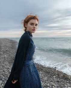 a woman in a blue dress is standing on the beach