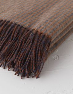 a brown and blue blanket laying on top of a white surface