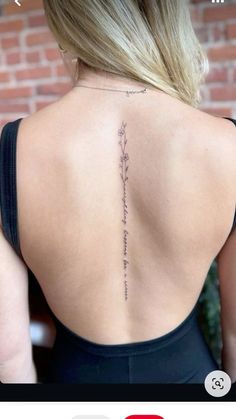 the back of a woman's neck with an inscription on her left shoulder and flowers in