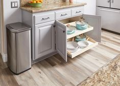 an open cabinet in a kitchen next to a counter with plates and bowls on it