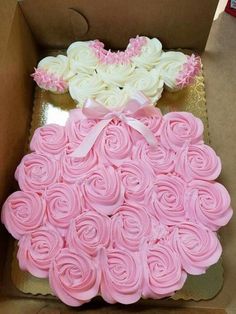 two cakes in a box with pink and white frosting roses on the top one is shaped like a dress