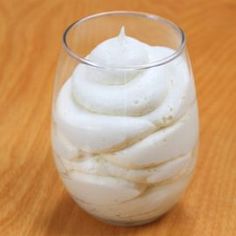 a glass filled with whipped cream on top of a wooden table