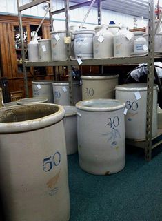 several large white barrels stacked on top of each other in a room with shelves and flooring