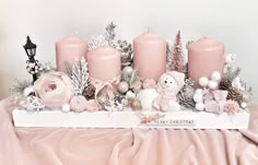 some pink candles are sitting on a table with other christmas decorations and ornaments around them