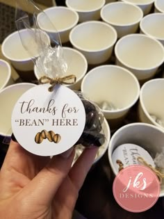 a person holding up a bag of peanut butter in front of many white bowls with chocolates on them