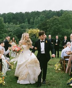 a bride and groom walk down the aisle after their wedding ceremony in an outdoor setting