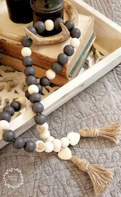 a wooden beaded necklace with tassels and beads sits on a bed next to an old book