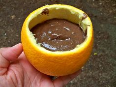 a hand holding an orange with chocolate in it