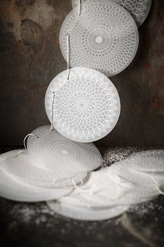 three white plates hanging from strings on a wall