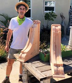 a man is standing next to some wooden planters and holding them on a bench