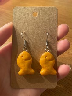 a person holding up a pair of earrings with yellow frosting on it's face