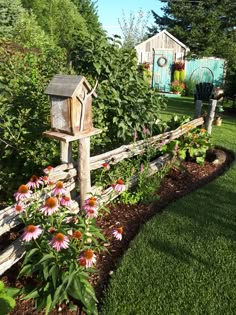 a garden with flowers and a bird house