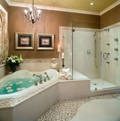 a bathroom with a tub, chandelier and two framed pictures on the wall