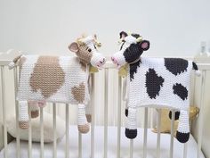 two crocheted cows standing next to each other in a crib